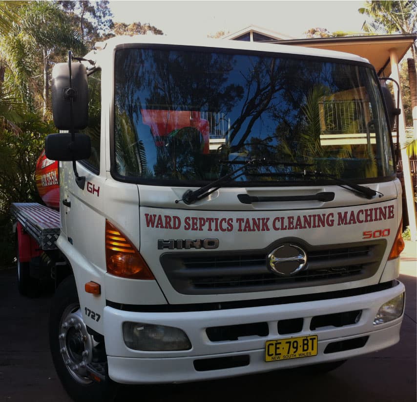 A front view of a white Hino 500 service truck with "WARD SEPTICS TANK CLEANING MACHINE" printed in red on the hood and a New South Wales license plate.