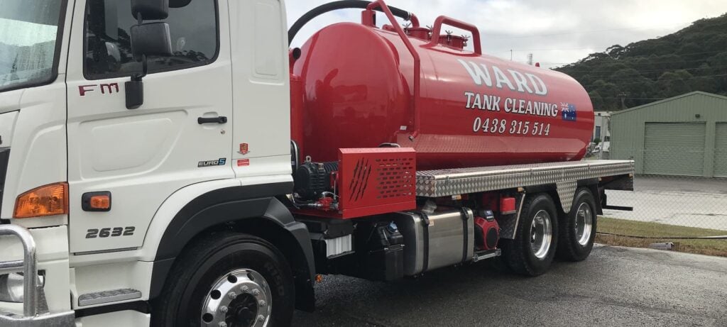 A white Hino commercial truck fitted with a large red liquid waste bearing the text "WARD TANK CLEANING" and a phone number.