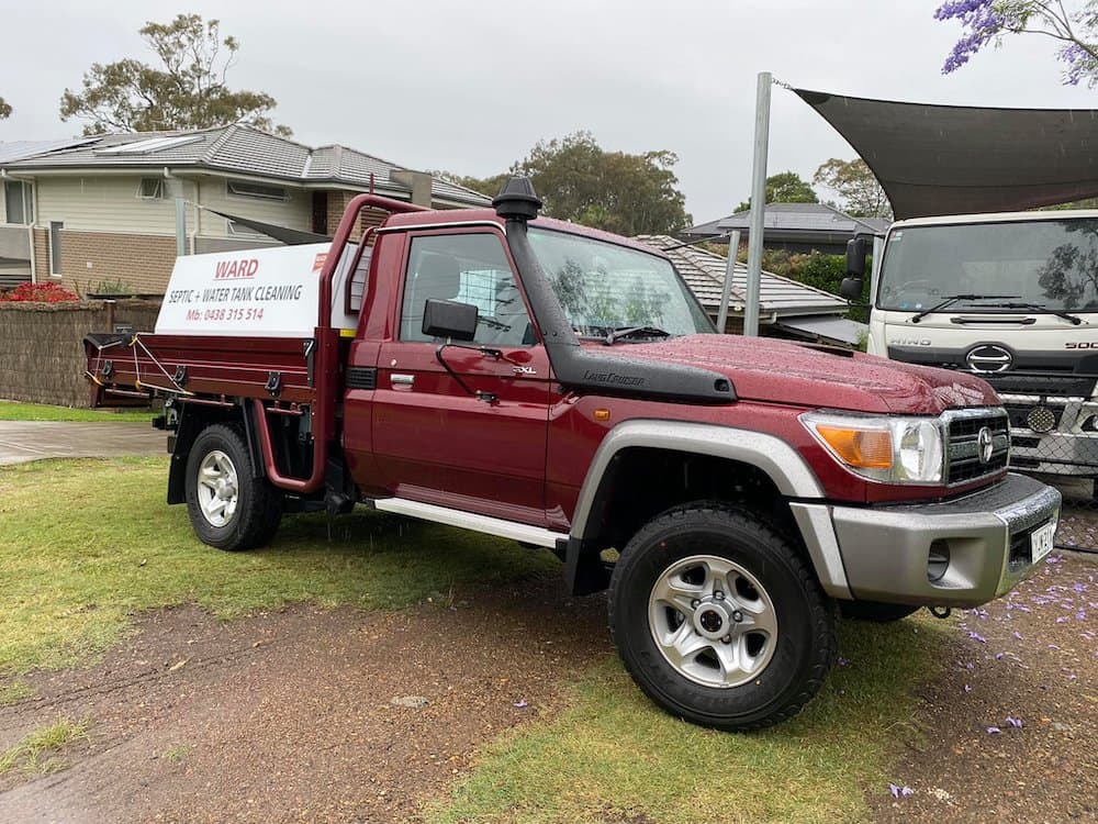A maroon Toyota LandCruiser service utility vehicle parked on grass