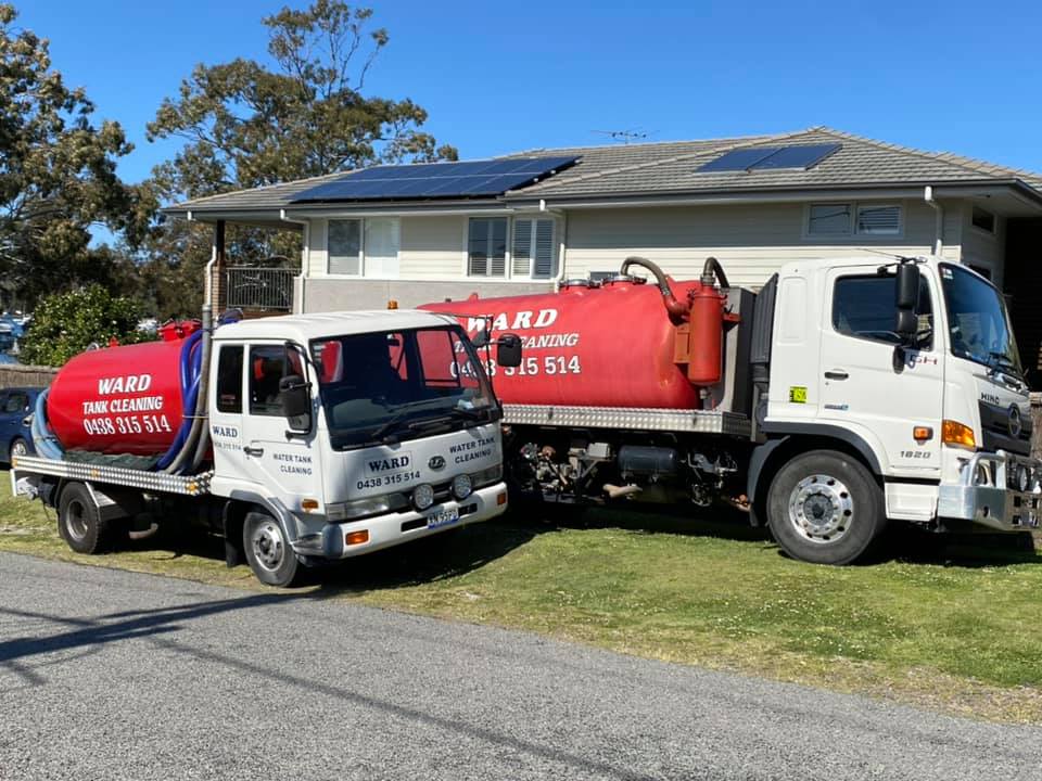 Two white "Ward Tank Cleaning" service trucks with large red tanks