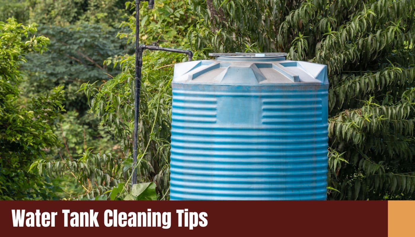 A large, ribbed blue polyethylene water storage tank positioned outdoors amidst lush green trees and foliage.