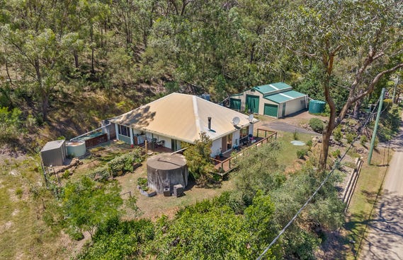 A rural residential property featuring a house with a tan roof