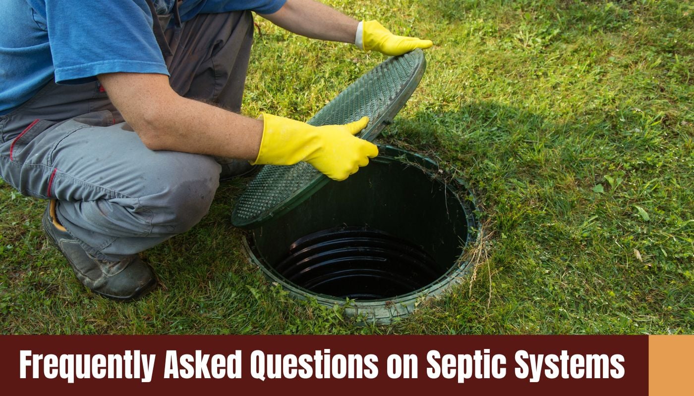 A person wearing yellow gloves opens a green septic tank lid in a grassy field