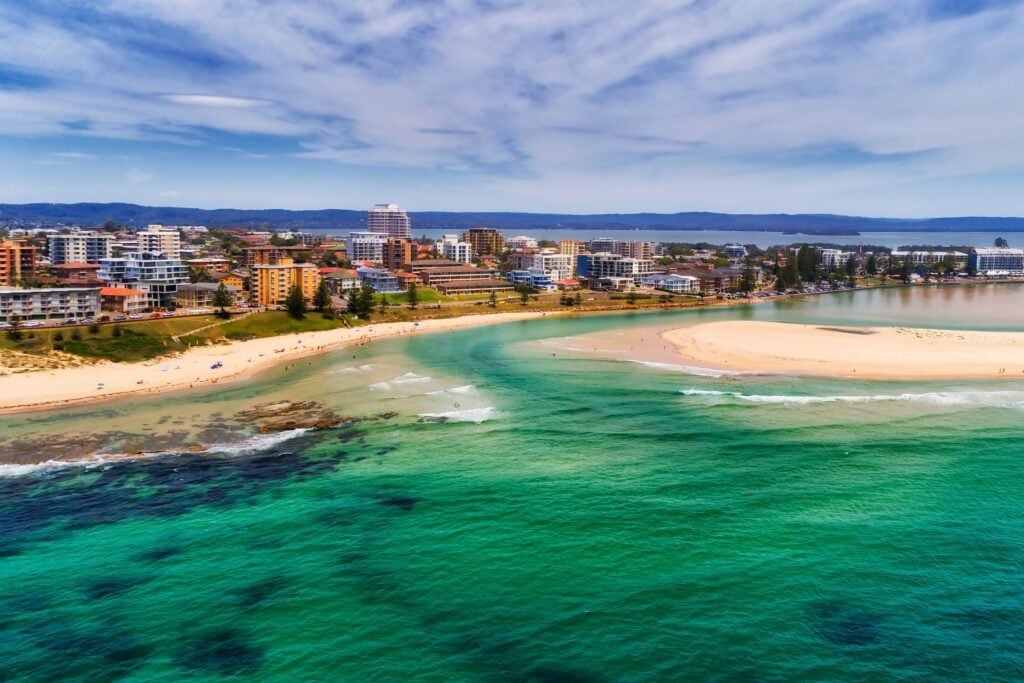 A coastal town of Tuggerah featuring turquoise ocean waters, sandy beaches and various low-rise apartment, buildings and hotels.
