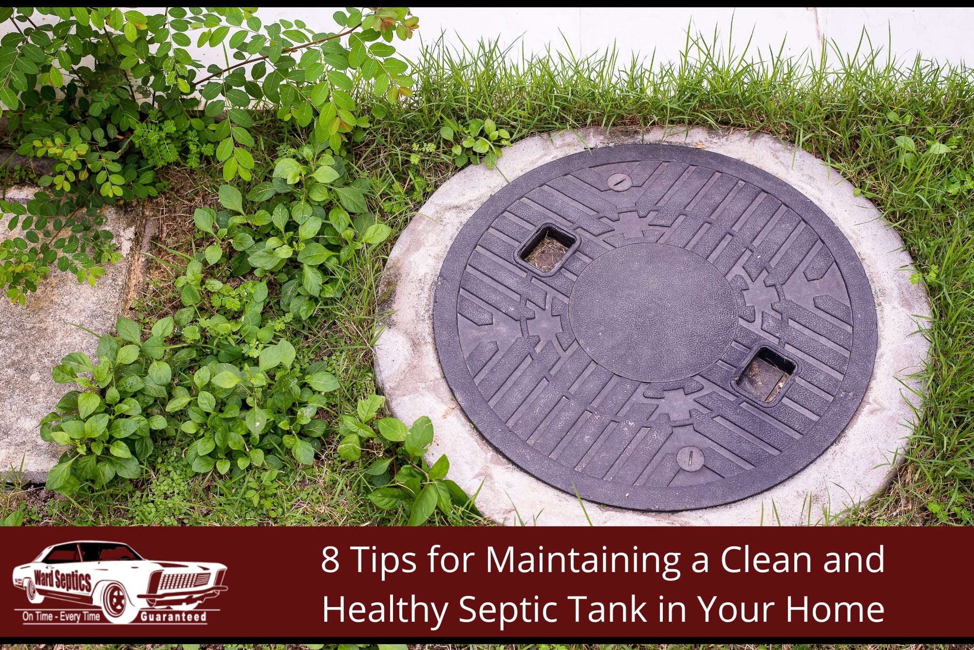 A circular patterned black plastic or composite manhole cover set in concrete amidst green grass and overgrown weeds.