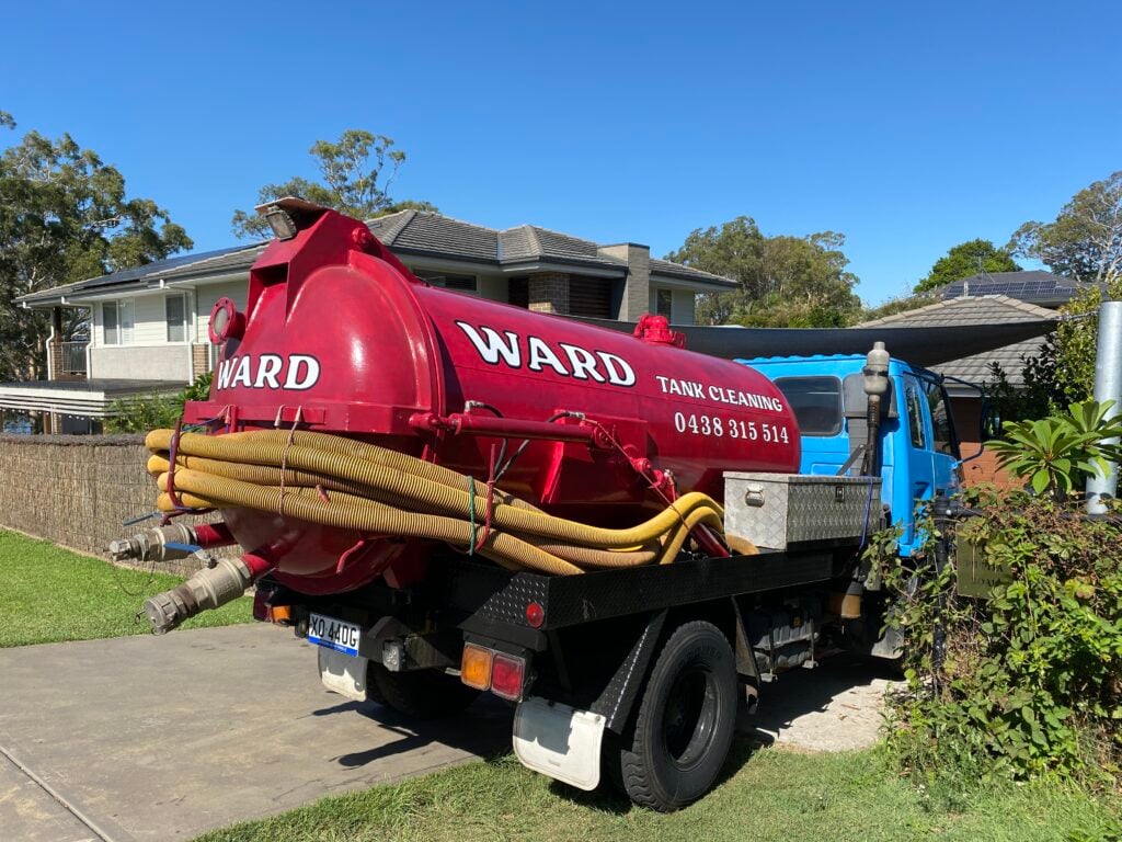 A blue liquid waste vacuum truck parked on a residential driveway.