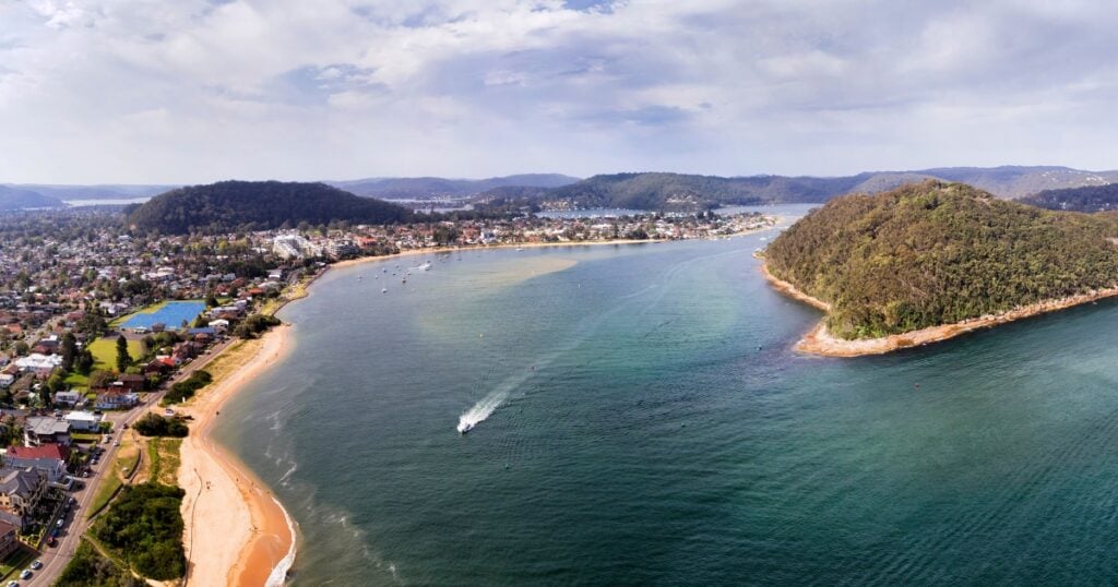 A coastal town nestled between lush green hills and a turquoise bay.