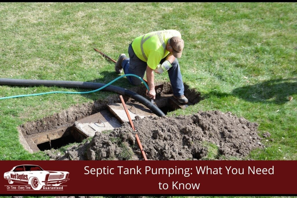 A worker in a high-visibility shirt servicing an uncovered underground septic tank on a lawn.