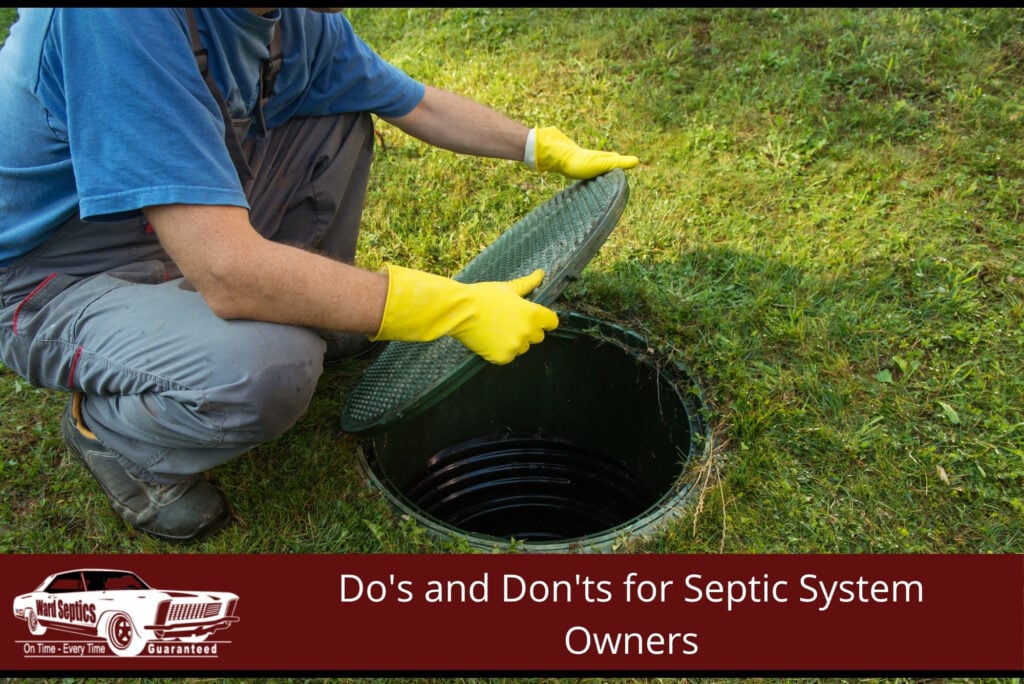 A technician wearing yellow gloves crouches down to lift a green textured plastic lid off an underground septic tank access riser.