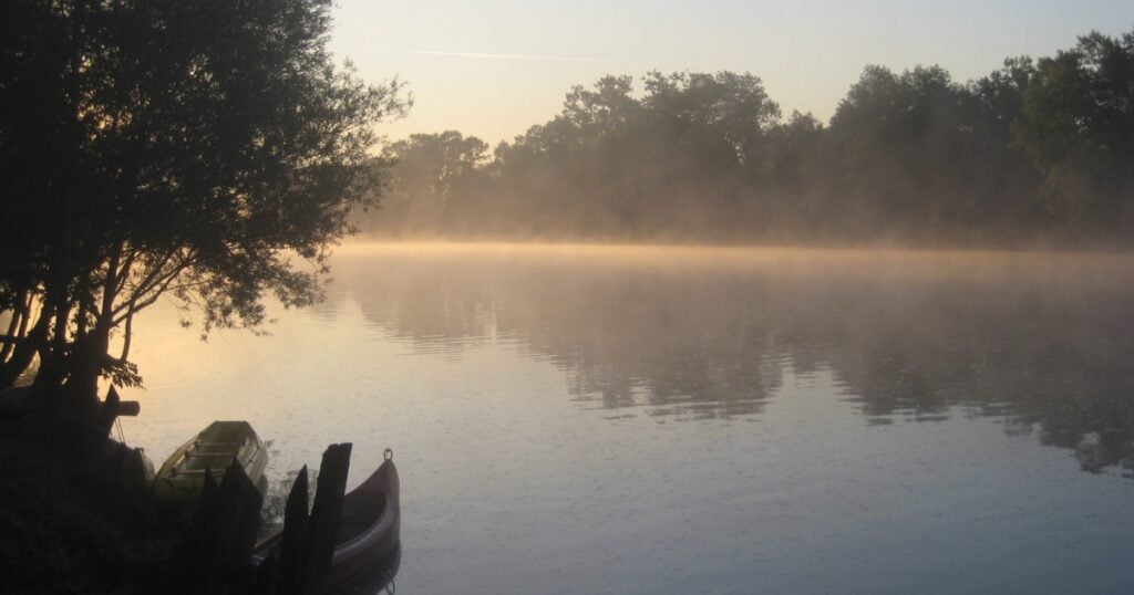 A peaceful Wyong River scene at sunrise with thick mist rising off the calm water.