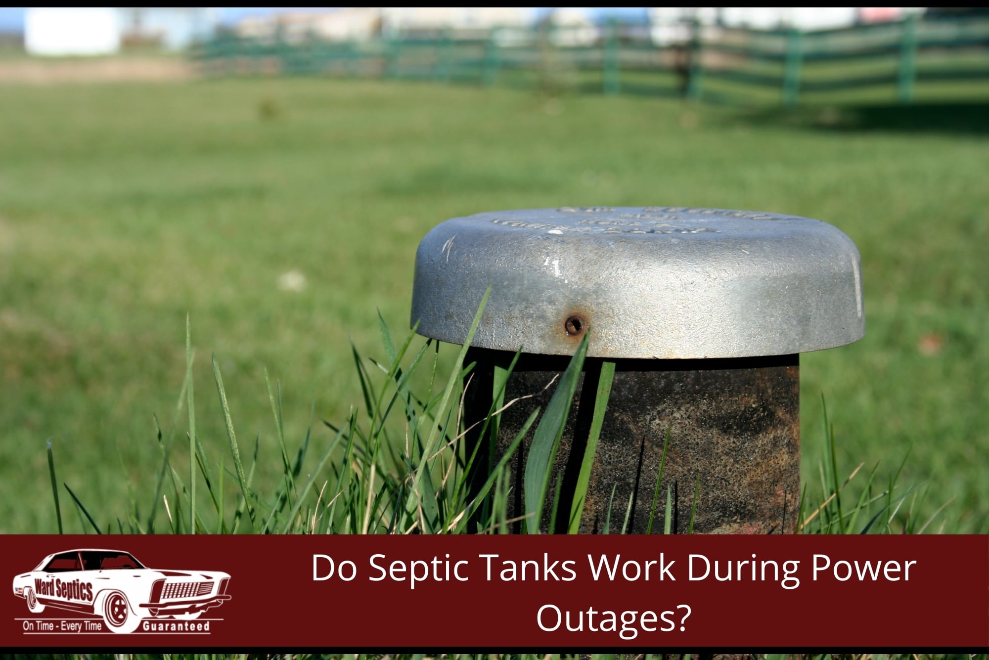 A metal well cap or vent pipe rising from a green grassy lawn, with a blurred fence line in the background.