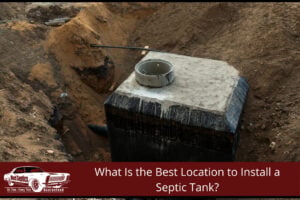 A newly installed concrete septic tank sits in a deep dirt excavation pit with connected piping